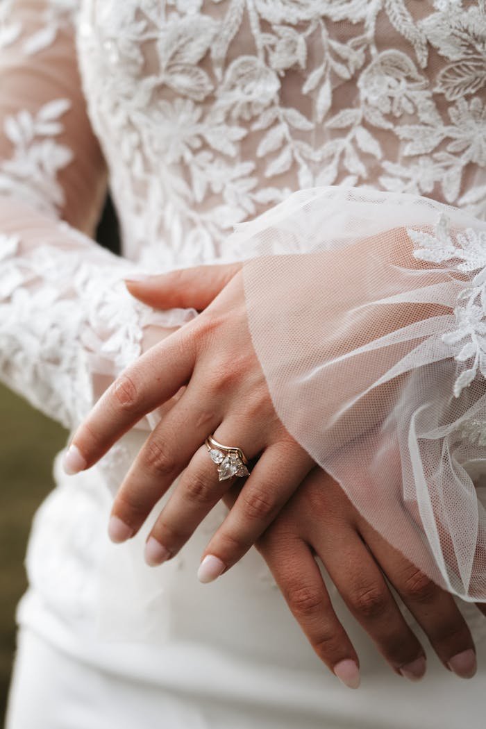 Close-up of a bride's hands with lace dress and elegant ring, capturing a timeless wedding moment.