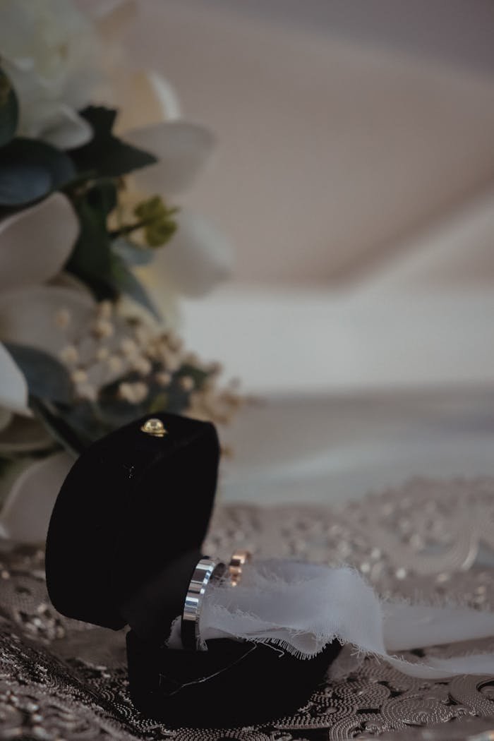 A stunning wedding ring inside a black velvet box, surrounded by white flowers, symbolizing love and commitment.